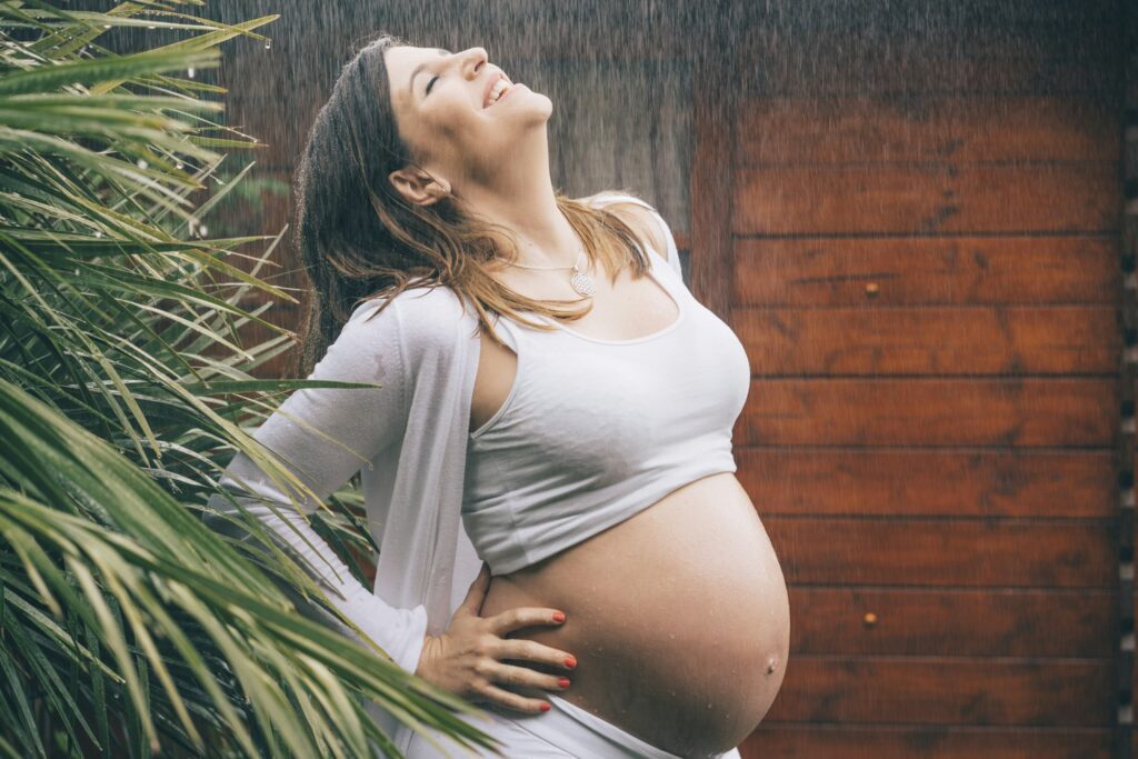 Beautiful pregnant woman posing in the rain.